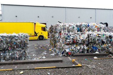 Kullanılmış plastik süt şişeleri ve kutular istiflenmiş balyalara doldurulmuş ve endüstriyel plastik atık geri dönüşüm tesisinde geri dönüşüme hazır.