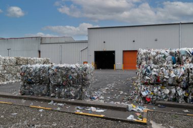 Kullanılmış plastik süt şişeleri ve kutular istiflenmiş balyalara doldurulmuş ve endüstriyel plastik atık geri dönüşüm tesisinde geri dönüşüme hazır.