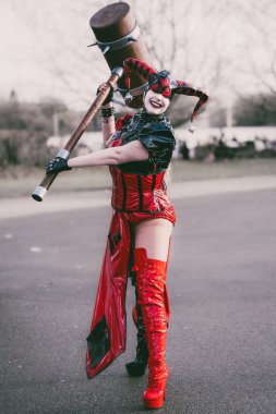 BIRMINGHAM, İngiltere - 30 Kasım 2024. Batman bayiliğinden Harley Quinn gibi giyinmiş bir kadın oyuncu bir komedi gösterisinde PVC kostümüyle gülüyor ve eğleniyor.