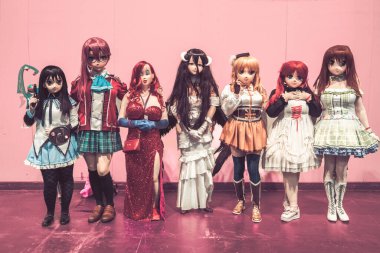 BIRMINGHAM, İngiltere - 30 Kasım 2024. Anime Kigurumi gibi giyinmiş, maskeli ve elbiseli bir grup kadın ve erkek kozoyuncu bir İngiliz çizgi roman fuarında.