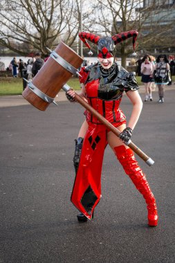 BIRMINGHAM, İngiltere - 30 Kasım 2024. Batman bayiliğinden Harley Quinn gibi giyinmiş bir kadın oyuncu bir komedi gösterisinde PVC kostümüyle gülüyor ve eğleniyor.