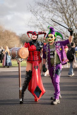 BIRMINGHAM, İngiltere - 30 Kasım 2024. Harley Quinn gibi giyinmiş bir bayan Cosplayer ve Batman 'den Joker kılığındaki bir erkek oyuncu bir çizgi roman gösterisinde gülüp eğleniyorlar.