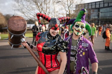 BIRMINGHAM, UK - NOVEMBER 30, 2024. A female cosplayer dressed as Harley Quinn and a male cosplayer as the Joker from the Batman franchise laughing and having fun in costume at a comic con event clipart