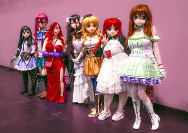 BIRMINGHAM, İngiltere - 30 Kasım 2024. Anime Kigurumi gibi giyinmiş, maskeli ve elbiseli bir grup kadın ve erkek kozoyuncu bir İngiliz çizgi roman fuarında.