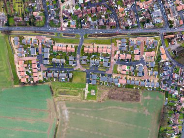 İngiltere 'de bir köyün kıyısındaki yeşil kuşaklı bir arazide yeni inşa edilmiş banliyö evleri üzerindeki havadan tepeden aşağı görüş.