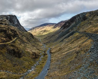 İngiltere 'nin Cumbria kentindeki İngiliz Lake District Ulusal Parkı' ndaki Honister Geçidi 'nin hava manzarası çevresindeki dağlar Honister Kayrak Madeni' ne doğru yol alıyor.