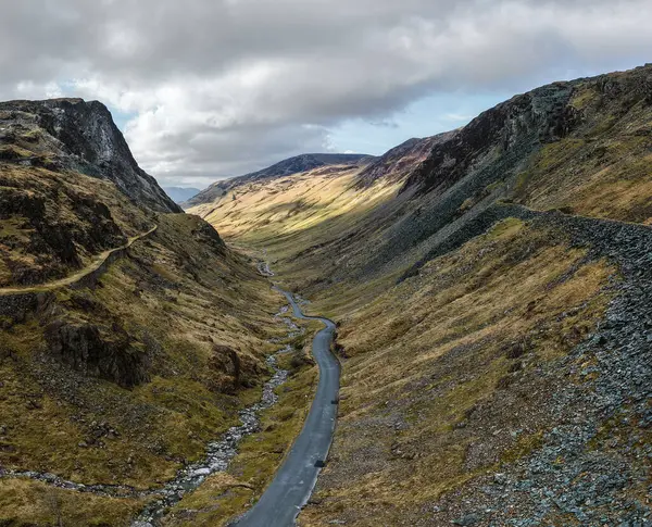 İngiltere 'nin Cumbria kentindeki İngiliz Lake District Ulusal Parkı' ndaki Honister Geçidi 'nin hava manzarası çevresindeki dağlar Honister Kayrak Madeni' ne doğru yol alıyor.