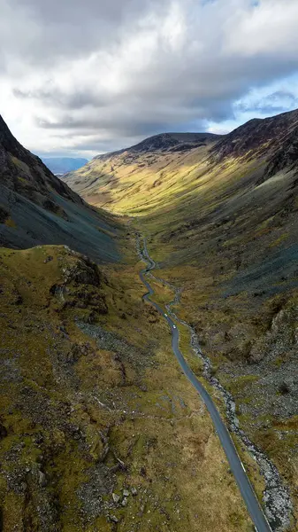 Cumbria, İngiltere 'deki İngiliz Lake District Ulusal Parkı' ndaki Honister Geçidi 'nin dikey hava manzarası. Etrafındaki dağlar Honister Kayrak Madeni' ne doğru ilerliyor.