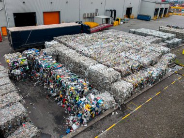 Polimer gıda ambalajı ve süt kutuları da dahil olmak üzere plastik atık balyalarının hava görüntüsü fotokopi alanı olan bir atık yönetim fabrikasında geri dönüşüme hazır