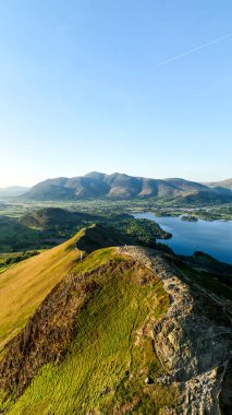 Derwent Water Gölü ve Keswick kasabası güneşli bir günde Kuzey Şelaleleri 'nin aşağısında bulunan İngiliz Lake District Ulusal Parkı' ndaki Catbell Dağı tepesi boyunca yürüme yolunun dikey manzarası.