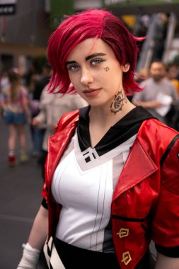 Savaşa hazır ve Vi gibi giyinmiş güzel bir kız oyuncu kameraya özgüvenle bakıyor.