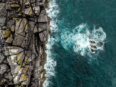 Kıyı erozyonu görüntüsünde sert granit kayalıklar ile kayalık kayalıkların üzerinden direkt olarak dalgalı denizlere doğru hava manzarası