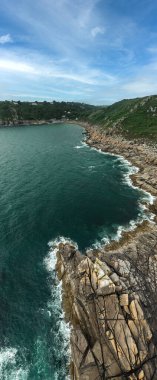 Cornwall 'daki Kertenkele Yarımadası' ndaki ilginç Cornish balıkçı köyünün kayalık kıyı şeridi ve tarihi limanı olan dikey hava manzarası.