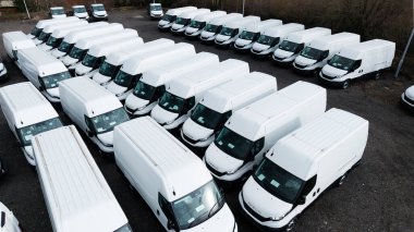 LEEDS, İngiltere - 24 Şubat 2025. Yeni inşa edilmiş beyaz Iveco minibüslerinin doğrudan üzerinde ticari bir rıhtımda bulunan hava görüntüsü gümrük vergileriyle birlikte ihracat ve ithalat için yüklenmeye hazır.