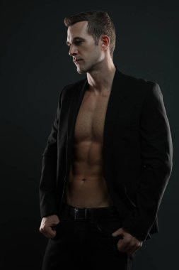 Sıradan seksi erkek manken ceketinin altındaki kaslarını gösteriyor.