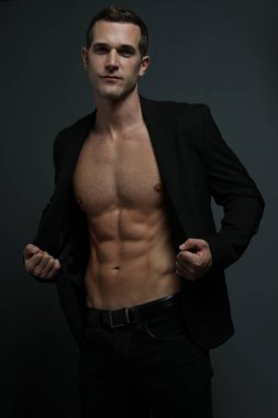 Seksi milyarder ceketini açıyor ve karın kaslarını gösteriyor.