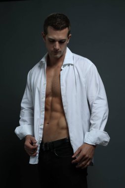 Erkek model açık yakalı gömlekle aşağıya bakıyor.