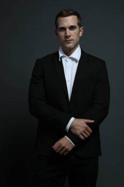 Keskin giyimli seksi adam ileriye bakıyor.