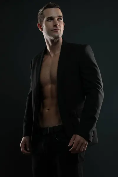 Takım elbiseli, üstsüz ve karın kaslı bir adam.