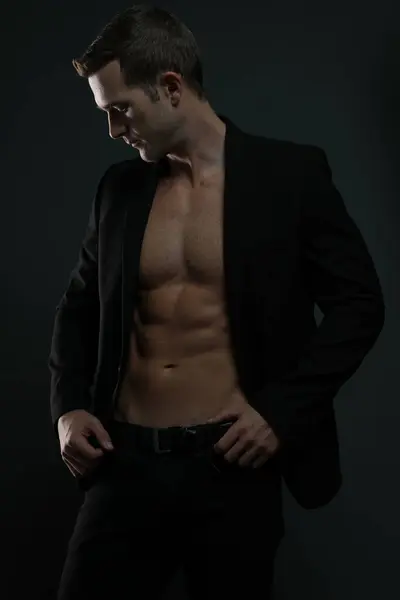 Ceketi açık tişörtsüz adam karın kaslarını gösteriyor.