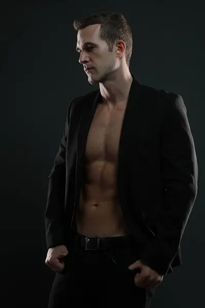 Sıradan seksi erkek manken ceketinin altındaki kaslarını gösteriyor.