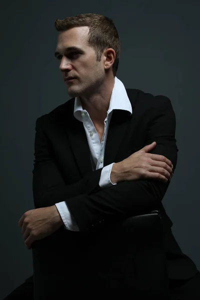 Smokinli bir adamın portresi sandalyede oturuyor.