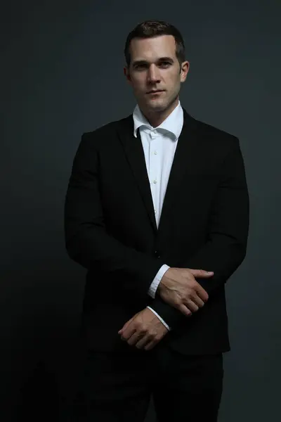 Keskin giyimli seksi adam ileriye bakıyor.