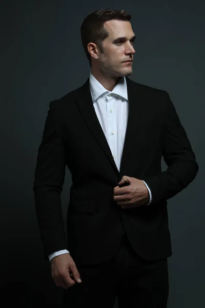 Takım elbiseli beyaz adam yan tarafa bakıyor.