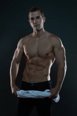 Beyaz tişörtlü üstsüz bir adam.