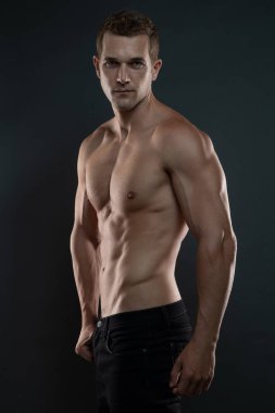 Siyah kotla öne doğru kıvrılan kaslı gömleksiz adam.