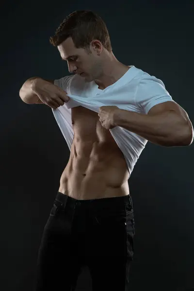 Adam gömleğini kafasının üstünden çekerek soyunuyor.