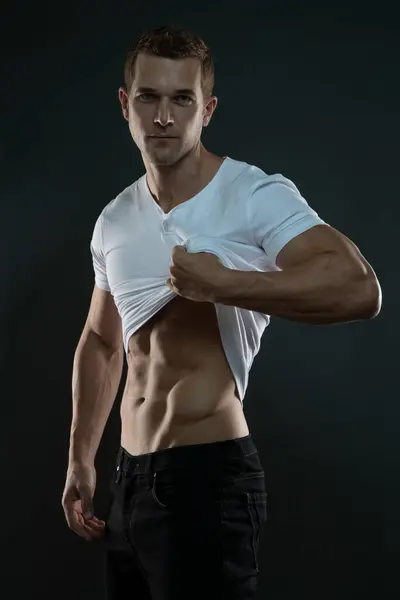 Seksi kaslı adam kameraya bakıyor tişörtünü kaldırıyor