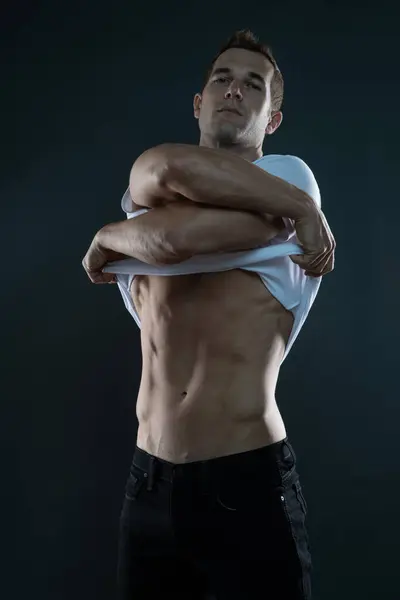 Yakışıklı erkek manken tişörtleri çıkarıyor.