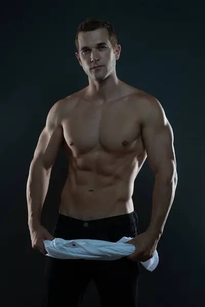 Beyaz tişörtlü üstsüz bir adam.