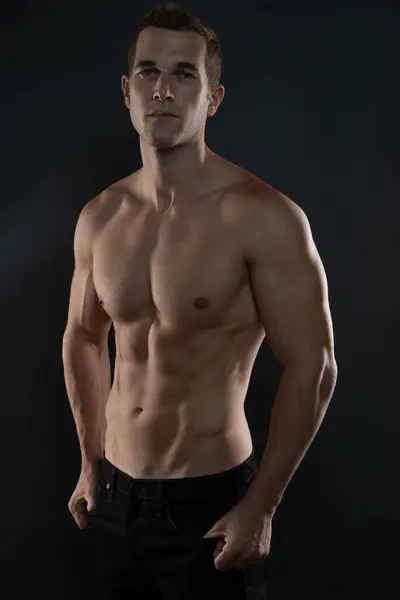 Çalışan adam kaslarıyla seksi poz veriyor.