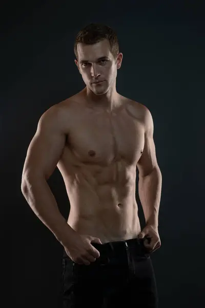 Gömleksiz Kaslı Adam ileriye bakıyor