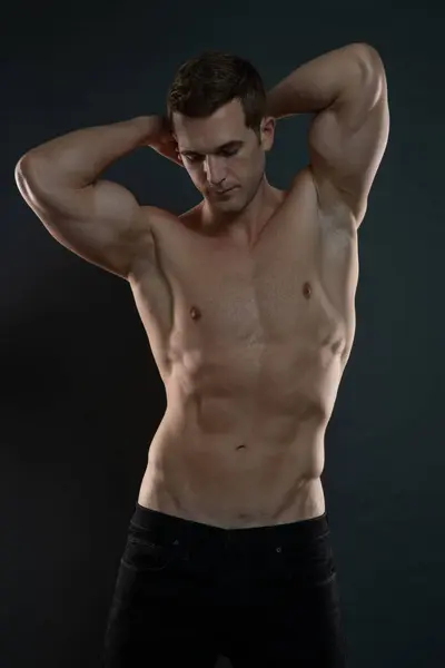 Elleri başının üstünde olan adam karın kaslarını gösteriyor.