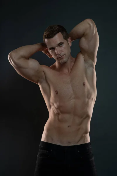 Genç erkek model kaslarını ve kaslarını gösteriyor.