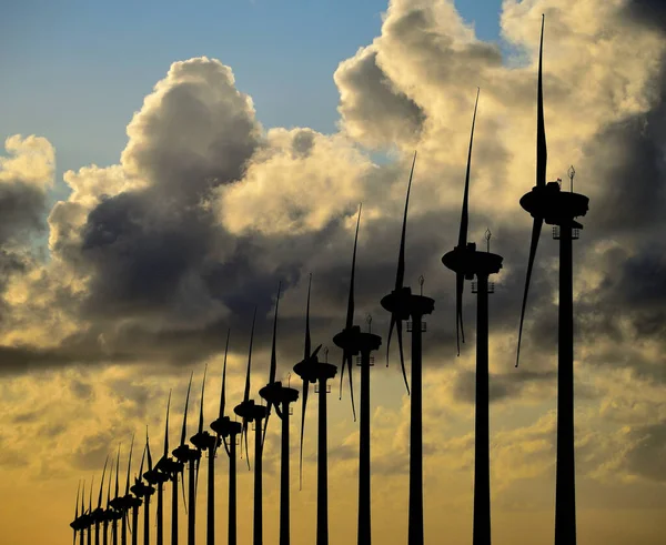 在日出时设置一排风力涡轮机 以云彩和天空为背景 — 图库照片