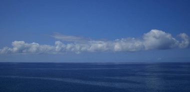 Ufkun muhteşem panoramik görüntüsü. Güzel alçak bulutlar, sakin deniz ve yoğun mavi gökyüzü.