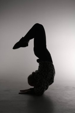 Gri arka planda poz veren genç bir balerin. Balerin siyah elbise ve dans ayakkabısı giyiyor. Çizgi çekimi - kız silueti.