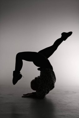 Gri arka planda poz veren genç bir balerin. Balerin siyah elbise ve dans ayakkabısı giyiyor. Çizgi çekimi - kız silueti.