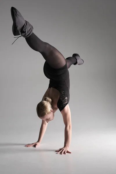 stock image Ballet dancer woman black dress on gray background, Ballerina posing and showing her flexibility on gray background in studio.