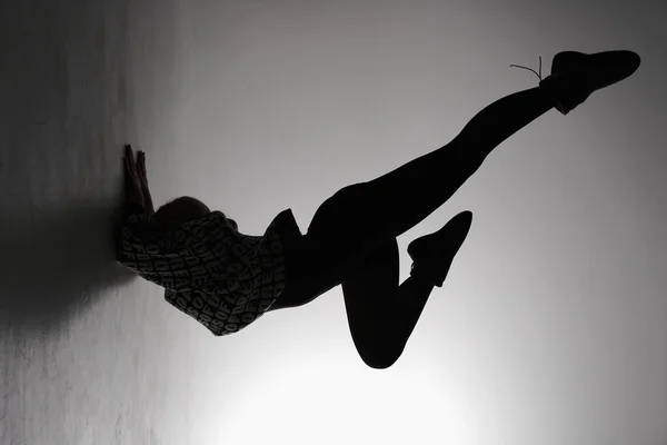 stock image young ballet dancer posing on a grey background. Ballerina is wearing in black dress and dance shoes. The outline shooting - silhouette of girl.