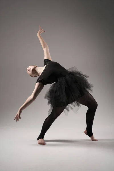 Ballerina Dancing with tutu Modern Ballet Dancer in dancer tutu, Gray Background. Dancer in Black clothes showing her flexibility posing on gray background in studio.