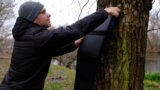 Mann Hängen Solarmodul Baum Zum Aufladen Von Smartphone Durch Multifunktionales — Stockvideo