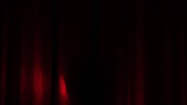 Zarif dansçı, sahnedeki aktris kırmızı bir arka planda sahneye çıkıyor ve daire ışığı ona odaklanıyor.