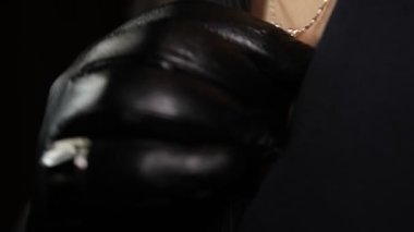 Siyah deri eldivenli ve siyah ceketli, göğsüne dokunan isimsiz bir kadın..