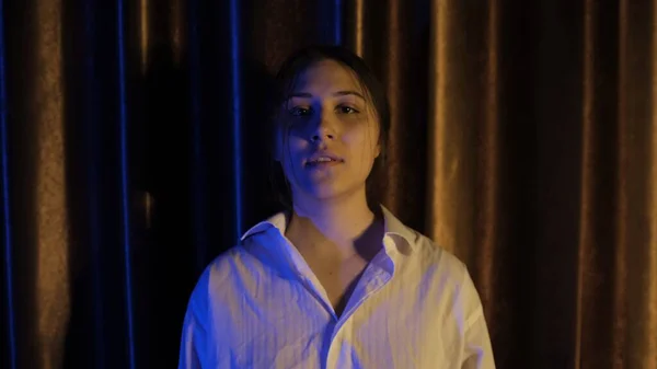 Nervous woman in white shirt in blue and yellow light breathing deeply with focus breathing, calming down after quarrel, Concept of abuse in relationships. Mental and physical violance woman.