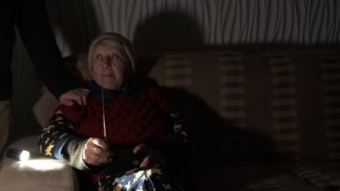 Büyükannem, Rusya 'nın terör saldırıları sırasında karanlıkta telsizi elinde tutuyor. Ailesi bacaklarını sarmak ve torununa sarılmak için sarılmış. Aile destek konsepti. Kazanmak için birlikte.